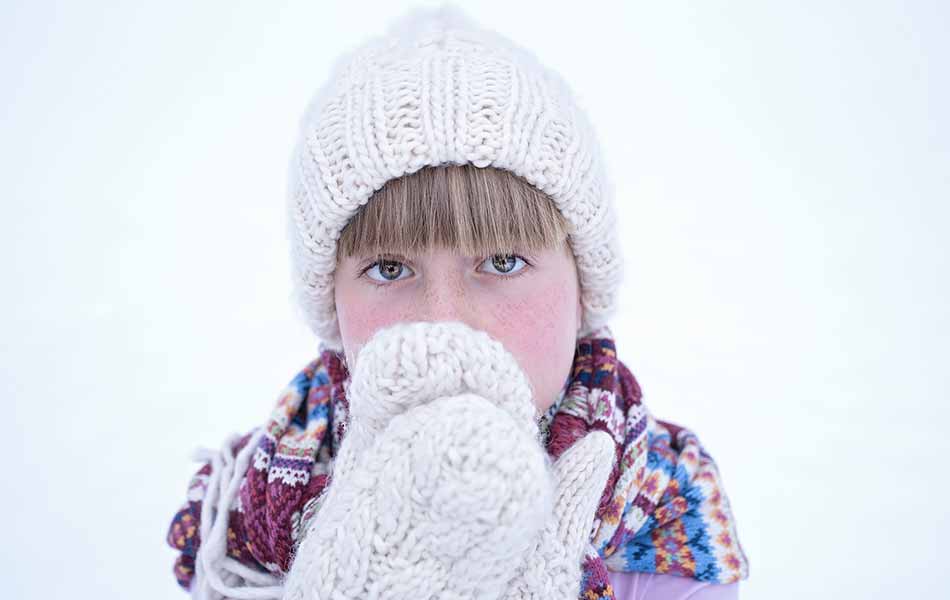 Enfant avec la peau des joues rouge du au froid.